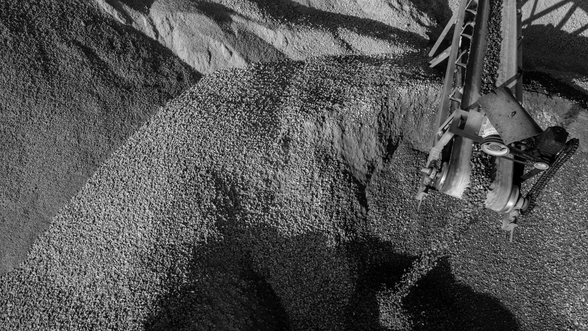 Conveyor building a stockpile of crushed rock, black and white