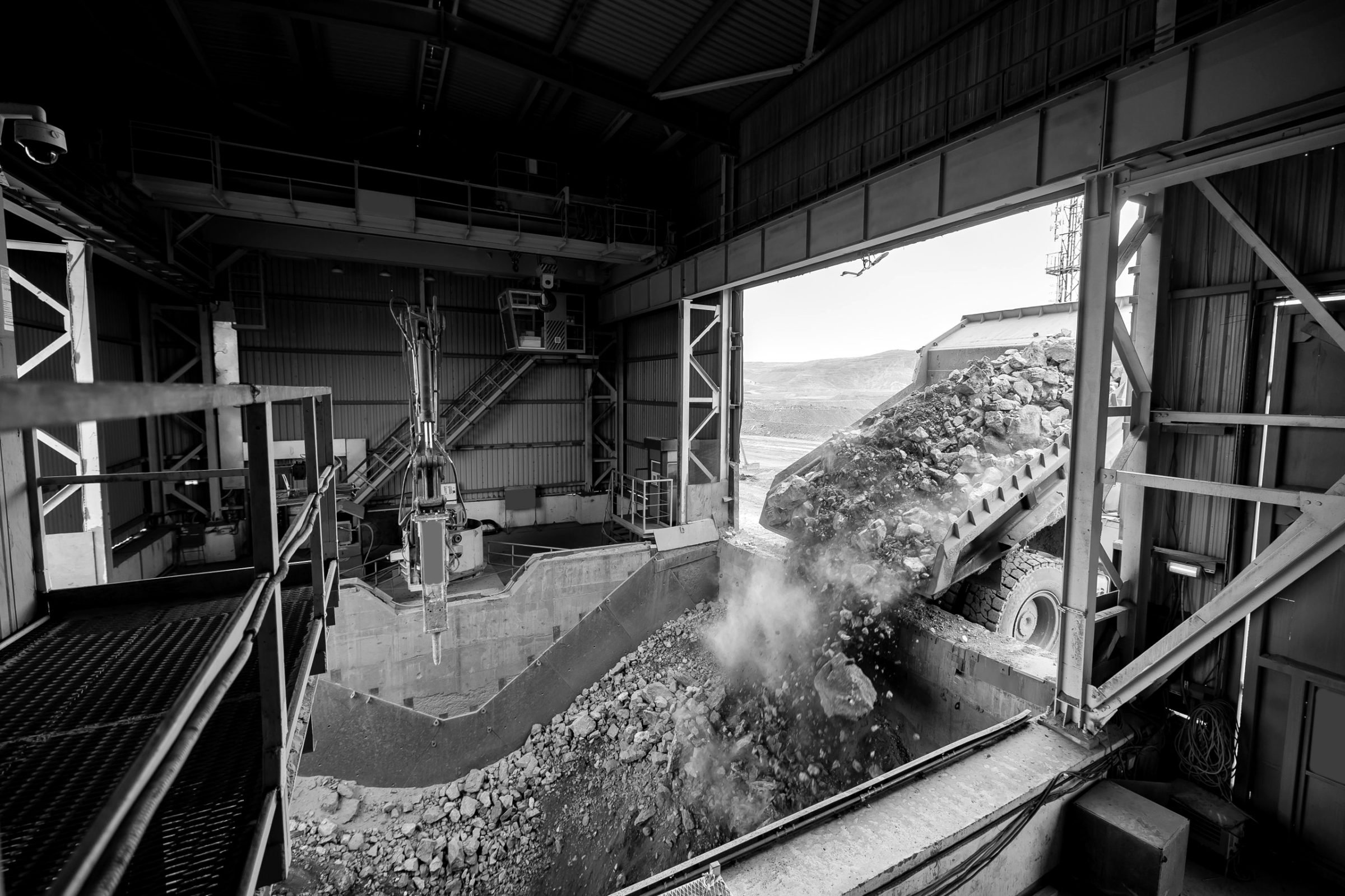 Haul truck dumping ore into a crusher, black and white